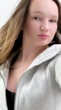 Sportif gri süveter giyen genç bir kız. Farklı duygular. Yüz ifadeleri. Beyaz arka planda kahverengi saçlar.