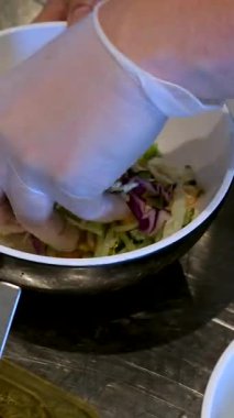 Sebzeli bir kase salata yapmak yeşillik, mayonez sosu, salatalık havucu, avokado ve mısır unu eldivenle hazırlamak, salata aşçısını elleriyle süslemek. Yüksek kalite