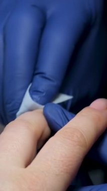 Güzellik salonundaki manikür ustasının manikür adım adım bütün hareketleri tırnak derisi lekesi temizleme jöle güçlendirici kadınların ellerini mavi eldivenlerle güçlendirme öz bakım sağlığına. Yüksek kalite 4k görüntü