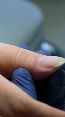 Güzellik salonundaki manikür ustasının manikür adım adım bütün hareketleri tırnak derisi lekesi temizleme jöle güçlendirici kadınların ellerini mavi eldivenlerle güçlendirme öz bakım sağlığına. Yüksek kalite 4k görüntü