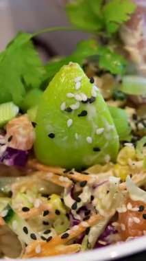 Sebzeli bir kase salata yapmak yeşillik, mayonez sosu, salatalık havucu, avokado ve mısır unu eldivenle hazırlamak, salata aşçısını elleriyle süslemek. Yüksek kalite