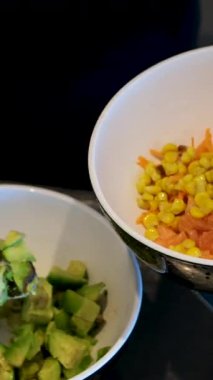 Sebzeli bir kase salata yapmak yeşillik, mayonez sosu, salatalık havucu, avokado ve mısır unu eldivenle hazırlamak, salata aşçısını elleriyle süslemek. Yüksek kalite