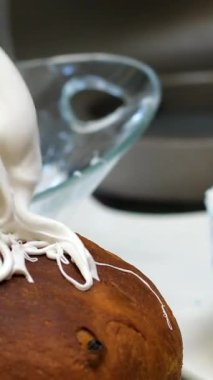 Yakın plan. Doğu Avrupa için geleneksel bir Rus ve Ukrayna paskalya pastası olan lezzetli Ortodoks Paskalya ekmeğine krema süren bir mutfak spatulası. Beyaz kremalı paskalya pastası..