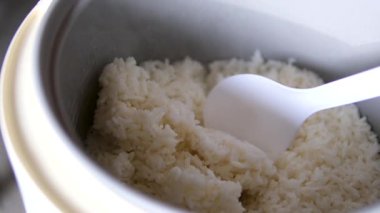Kaşıkla karıştırılmış beyaz Tayland yasemin pilavı pilavı pilav tenceresinde yavaş çekimde yakın çekim. Yüksek kalite 4k görüntü