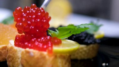 Sandviçin üstüne kaşık havyarı. Kırmızı havyar ve tereyağlı taze ekmek. Klasik lüks aperatif, gurme aperatifler ve zarif parmak yemekleri. - Evet. Yüksek kalite 4k görüntü