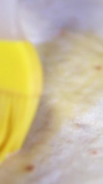 Bir fırçanın sarmal şekilli bir börek pastasına yumurta yıkama uygulayıp pişirmeye hazırladığı yakın çekim görüntüsü. Yüksek kalite 4k görüntü