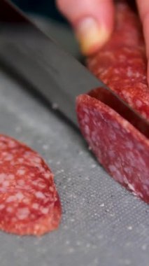 Kadın mutfakta keskin bir bıçakla salam kesiyor. Sosisleri titizlikle dilimleme, üniforma sergileme aperatifler, mezeler, mezeler veya tarifler için idealdir. Sosis dilimleme