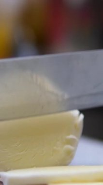 Fesleğen yaprağı, beyaz ırk kızı mozzarellayı dikkatlice mutfak masasında dilimliyor. Genç bir ebeveyn bir parça peyniri bıçakla keser. Çeşitli sebze ve peynir malzemeleri kullanır.