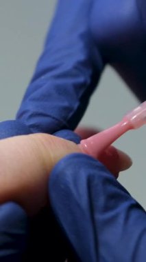 Kendi kendine manikür hizmeti. Manikürcü pembe jöleyle oje sürüyor. Tırnak cilası başvurusu. Manikürlü pembe tırnaklar. Yüksek kalite 4k görüntü