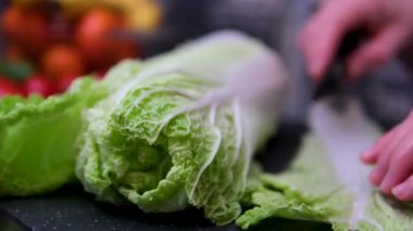 Çin lahanası mavi bir kesme tahtasıyla dilimleniyor, pişirmeye hazır, yanında paslanmaz çelik bir kase ile. Yüksek kalite 4k görüntü