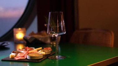 Peynir tabağı ve kırmızı şarap. Peynir tahtasının üzerinde duran farklı peynirlerle kırmızı şarabı cama dökmek. Siyah bir arkaplan ve şarap üzerinde nefis bir peynir seçimi sunuldu.