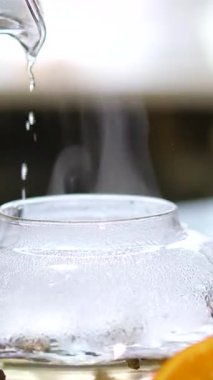 Portakallı, limonlu ve limonlu çayı şeffaf çaydanlıktan bardağa doldurmak. Arka planda bal ve krep ile çay demlemek. Yavaş çekim çayı. Tam HD. Yüksek kalite 4k görüntü