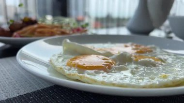 Tabakta sahanda yumurta. Kahvaltı için beyaz bir tabaktan çatallı yumurta sarısı al.