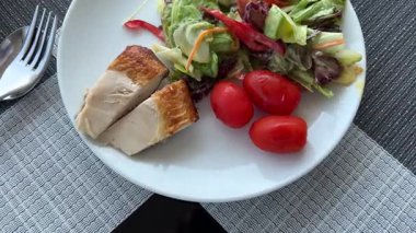 Beyaz bir tabakta vişneli domatesler tavuk parçaları ve salata nefis dengeli öğle yemeği kilo kaybı için kişisel bakım. Yüksek kalite 4k görüntü