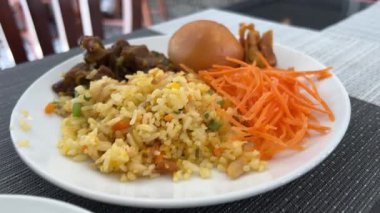 Restoran masasında bir tabak kızarmış pirinç ve karides, hareket manzaralı. Taze havuç ve çırpılmış yumurta.