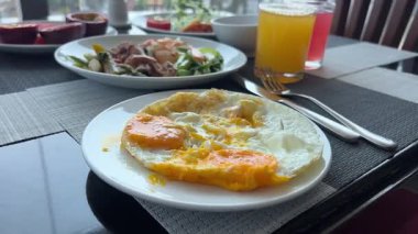 Restoranda ya da kafede kahvaltı. Reçelli ve ekşi kremalı ev yapımı süzme peynir krepleri ve İngiliz kahvaltısı, yumurta, salata ve kızarmış bacon. Lezzetli bir sabah yemeği.,