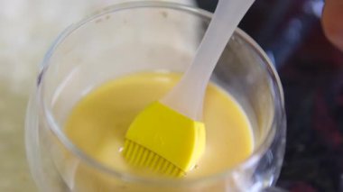 Yeni hazırlanmış böreklere yumurta yıkama makinesini dikkatlice fırçalarken şefin ellerini çeken yakın plan bir fotoğraf. Parlak bitiriş onları profesyonel bir mutfakta pişirdikleri için hazırlıyor. Yakın çekim.