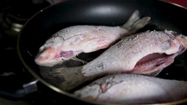 Ev yemeği. Kızartma tavasında ayçiçeği yağıyla sazan balığı kızartan bir kadın. Yüksek kalite 4k görüntü