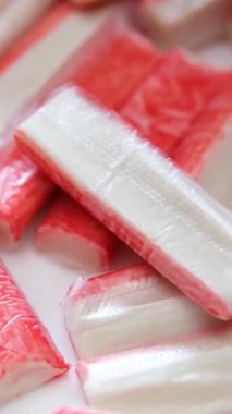 Kırmızı yengeç çubuklarını kesen kadın elleri ya da tahta kesme tahtasındaki bıçakla surimi. Evde yemek pişirmek. Yüksek kalite 4k görüntü