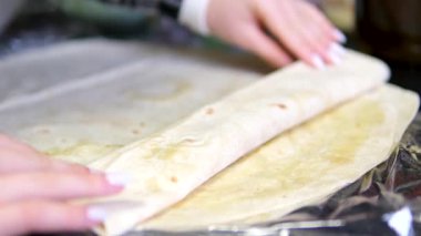 Donör hazırlama işlemi, mutfak önlüğü giymiş genç bir kadın dilimlenmiş salatalık, lahana ve tavukla pita ekmeği sarar. Yüksek kalite 4k görüntü