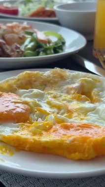 Restoranda ya da kafede kahvaltı. Reçelli ve ekşi kremalı ev yapımı süzme peynir krepleri ve İngiliz kahvaltısı, yumurta, salata ve kızarmış bacon. Lezzetli bir sabah yemeği.,