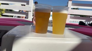 Plastik bardaklar ve soğuk bira. Kumsalda, havuzun yanında. Kumsalda ya da piknik için yeniden kullanılabilir sofra takımı. Yüksek kalite 4k görüntü
