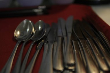 Gri bir bez peçeteye yerleştirilmiş kaşık, çatal ve bıçaktan oluşan kırsal bir sofra takımı klasik cazibe ve işlevselliği çağrıştırıyor. Yüksek kalite fotoğraf