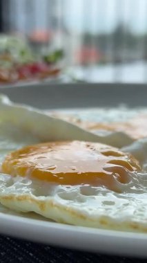 Tabakta sahanda yumurta. Kahvaltı için beyaz bir tabaktan çatallı yumurta sarısı al.