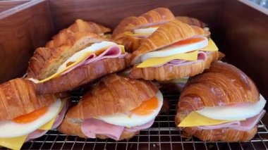 Kruvasan sandviçli lezzetli kahvaltı haşlanmış yumurta, avokado, yumuşak peynir, mozzarella ve domatesli beyaz arka planda çatallar. Yüksek kalite 