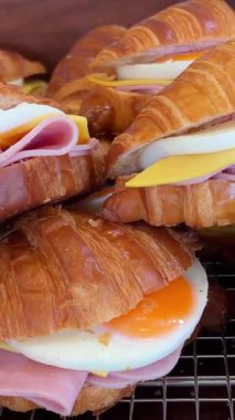 Kruvasan sandviçli lezzetli kahvaltı haşlanmış yumurta, avokado, yumuşak peynir, mozzarella ve domatesli beyaz arka planda çatallar. Yüksek kalite 