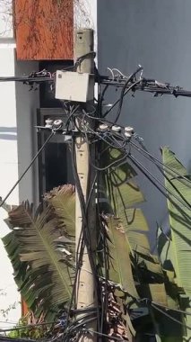 Parlak mavi gökyüzü küçük bir kasabadaki elektrik hatlarını ortaya çıkarıyor. Vietnam Şehri Danang direkleri ve telleri