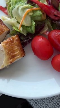 Beyaz bir tabakta vişneli domatesler tavuk parçaları ve salata nefis dengeli öğle yemeği kilo kaybı için kişisel bakım. Yüksek kalite 4k görüntü