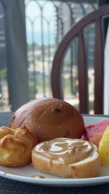 Kız kahvaltı etmek için masaya oturur çatal bıçak bacaklarını alır güzel, tanınmayan bir kadın kahvaltı için büfeye tabak getirir. Yüksek kalite 4k görüntü