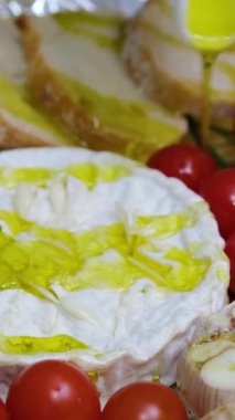  Konum. Bir ev hanımı mutfak masasındaki salataya zeytinyağı ekler. Genç bir kadın çeşitli sebze ve peynirlerle zeytinyağı döküyor. Domatesli ve kızarmış ekmekli camembert peyniri pişir.