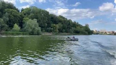 Ufuk çizgisine doğru İHA uçuşu ve Illinois Ormanı 4k 'ta açık yeşil yapraklı, beyaz kabarık bulutlu ve mavi gökyüzlü bir göl üzerindeki ağaç hattı. Yüksek kalite 4k görüntü