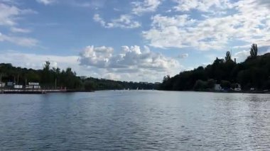 Ufuk çizgisine doğru İHA uçuşu ve Illinois Ormanı 4k 'ta açık yeşil yapraklı, beyaz kabarık bulutlu ve mavi gökyüzlü bir göl üzerindeki ağaç hattı. Yüksek kalite 4k görüntü