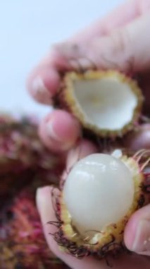 Kıllıyı çıkarmak için kolay bir yöntem. Bir egzotiğin kırmızı kabuğu. Tropik rambutan meyvesi. Güneydoğu Asya 'da tatlı bir lezzet. 4K görüntü 2160p. Yüksek kalite 4k görüntü