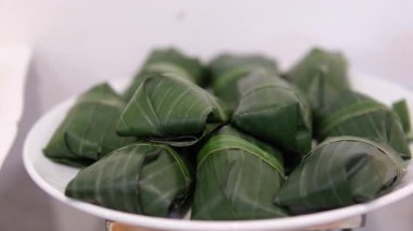 Muz yapraklarına sarılı taze yengeçler, yerel bir pazarda satışta sergileniyor, geleneksel deniz ürünleri hazırlıklarını vurguluyorlar..