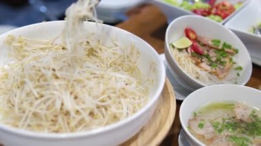 Geleneksel Vietnamca otlar, et, Pirinç Noodle Pho bo çorba suyu. Pho bo chopsticks, kase kaşık. Metin için yer. Üstten Görünüm. Ahşap masa arka plan Asya yemek Pho bo. Vietnamca çorbası