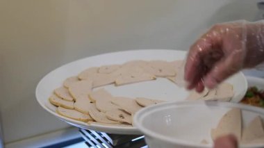 Fransız ekmeğiyle dilimlenmiş domuz pastırması. Sosis retro-stil yemek tepsisinde ve yemek kağıdında. Yavaş çekim kaydırağın üzerinde. Taze marul yaprakları da kullanıyoruz.