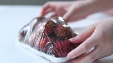 Arka planda bir Rambutan meyvesi ya da Nephelyum Lappaceum 'u tutan ve açan birinin yakın çekimi. Yüksek kalite 4k görüntü