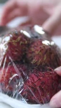 Arka planda bir Rambutan meyvesi ya da Nephelyum Lappaceum 'u tutan ve açan birinin yakın çekimi. Yüksek kalite 4k görüntü