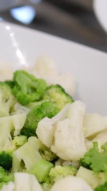Delicious fresh vegetables steamed carrots, broccoli, cauliflower on a black plate on a dark concrete background
