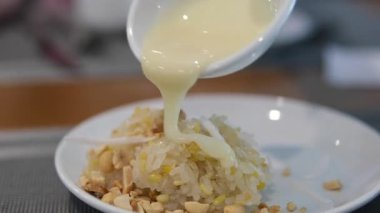 Bir el ahşap bir masanın üzerine hindistan cevizi sosu döker. Parlak ışıklandırma canlı renkleri güçlendirir. Yüksek kalite 4k görüntü