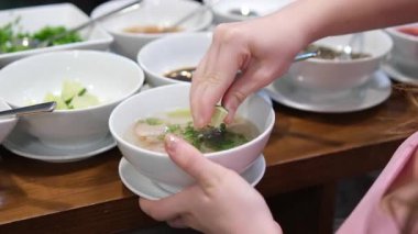 Vietnam Pho bo Çorbası taze ve ev yapımı mutfağa vurgu yaparak, açık büfede büyük kaplardan sıcak çorba servis eden limon damlaları serpiştiriyor. Yüksek kalite 4k görüntü