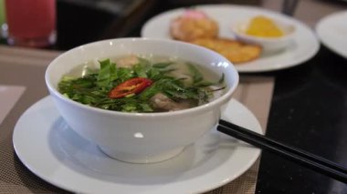 Beyaz tabakta fesleğen ve kırmızı biberli Vietnamlı pho bo bo