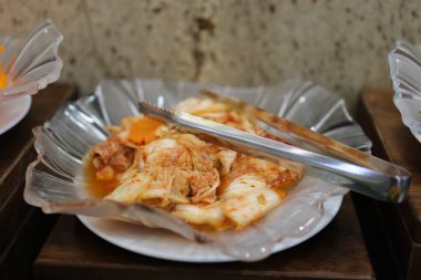 Ev yapımı kimchi, bir Kore mirası tabağı, küçük bir kasede servis maşasıyla servis ediliyor..