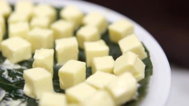 Tereyağı dilimleri bir tabağa konur, kek pişirmek için tereyağını küp şeklinde keser, Tahta üzerinde Taze Tereyağı 'nın Tüm Parçaları, Yakın plan, Makro ve Döndürme. Doğal Tereyağının İzole Arkaplanı