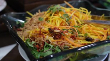 Sarı rende mangoyu ince şeritlere ayırır ve beyaz kasede biriktirir. Canlı sarı mango parçaları jülyen renginde. Basit yemek hazırlığı..