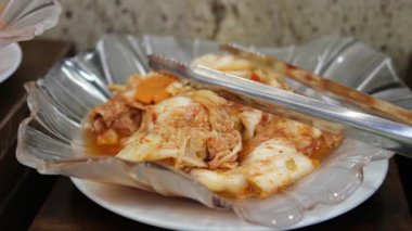 Ev yapımı kimchi, bir Kore mirası tabağı, küçük bir kasede servis maşasıyla servis ediliyor..
